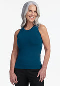 Smiling older woman with long gray hair wears the Woolx Ava Tank Top in Majolica Blue and black pants, standing against a plain white background. | Tam is 5’8.5”, wearing a size S