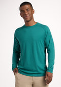 A man smiles against a plain background, wearing the Woolx Essential Tee - Woodland Mini Stripe in teal, paired with beige pants and one hand in his pocket. | Trell is 6’2”, wearing a size M