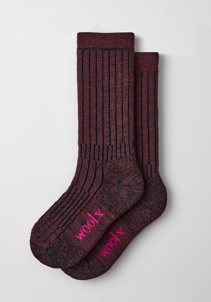 Two warm violet mid-calf Woolx socks with “woolx” in pink, made from moisture-wicking Merino wool.
