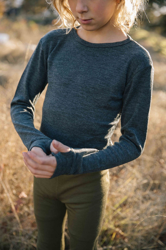A child wearing a long-sleeved gray thermal top outdoors.