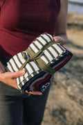 A person holding a bundle of striped fabric pieces, likely made of merino wool, intended for crafting or quilting.